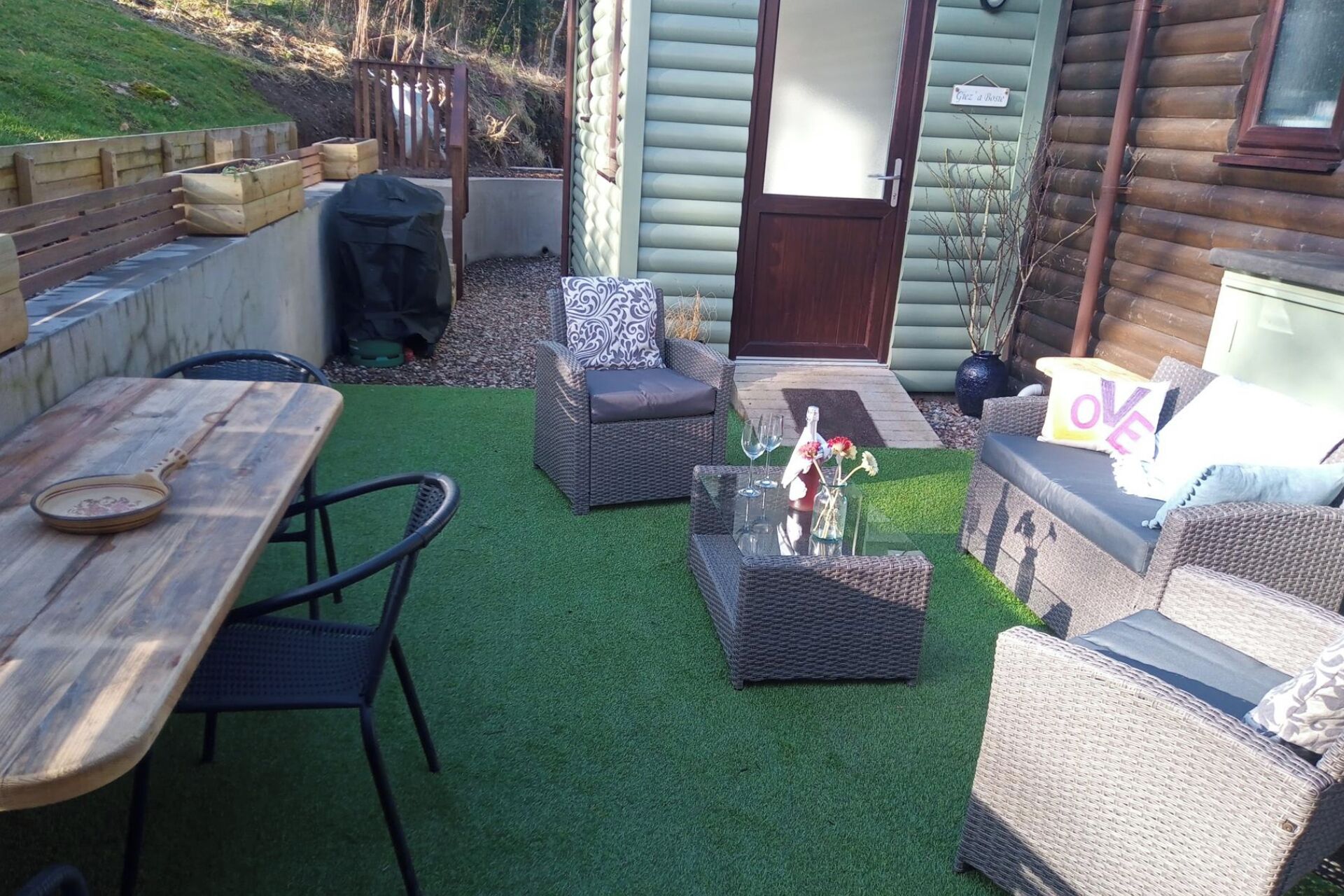 A patio with wicker furniture, a glass table, and a wooden table.