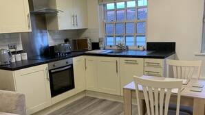 A modern kitchen with white cabinets, a stainless steel range hood, a built-in oven, and a window with a view of the outside. - 2-Bed Duplex Sleeps 3 with Fireplace (doncaster)