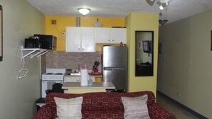 A compact living space with a kitchenette, a sofa with cushions, and a small dining table.
