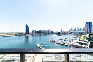 Un puerto deportivo con barcos amarrados, rodeado de edificios modernos y un cielo despejado.