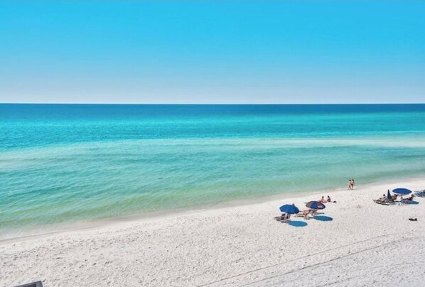 Relax on the wide, sandy beach with comfortable lounge chairs and umbrellas.