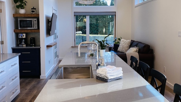 A modern kitchen with a central island, stainless steel appliances, and a large window providing natural light.