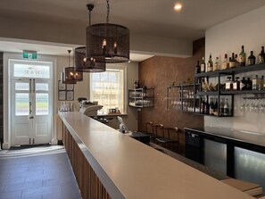 A bar area with a long counter, multiple hanging lights, and a wine and liquor display. - The Oak & Anchor Hotel (Port Fairy)