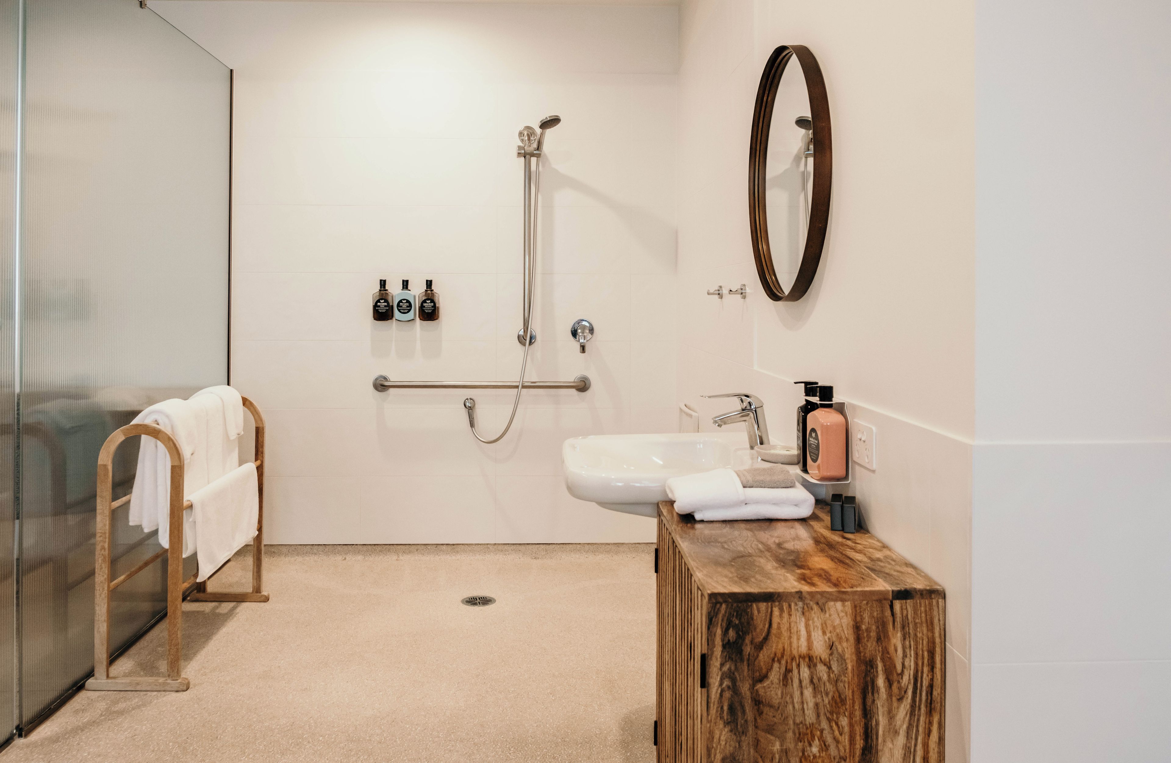 A modern bathroom with a glass shower enclosure, a wooden vanity with a sink, and a mirror.