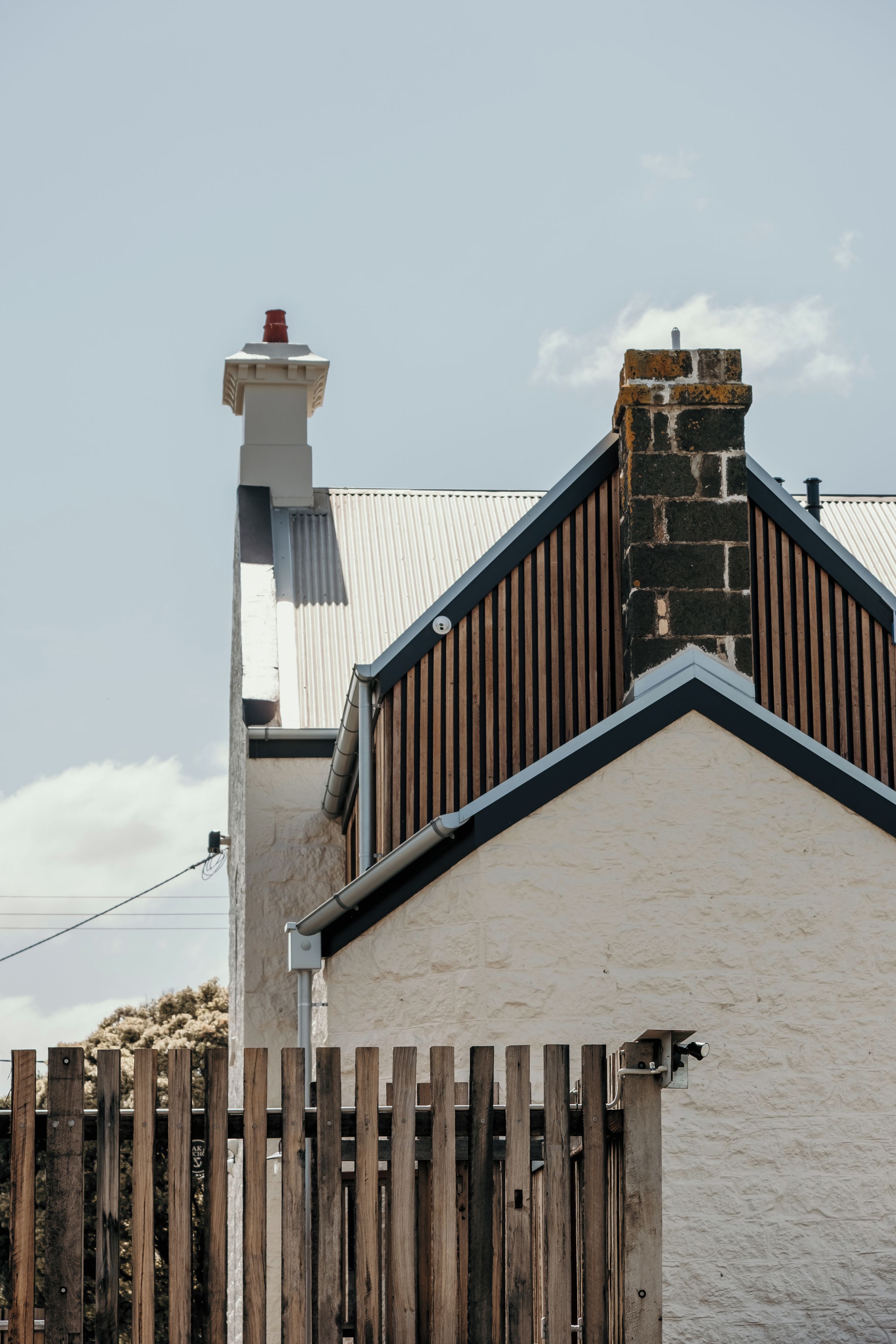 A building with a white facade, a wooden fence, and a chimney.