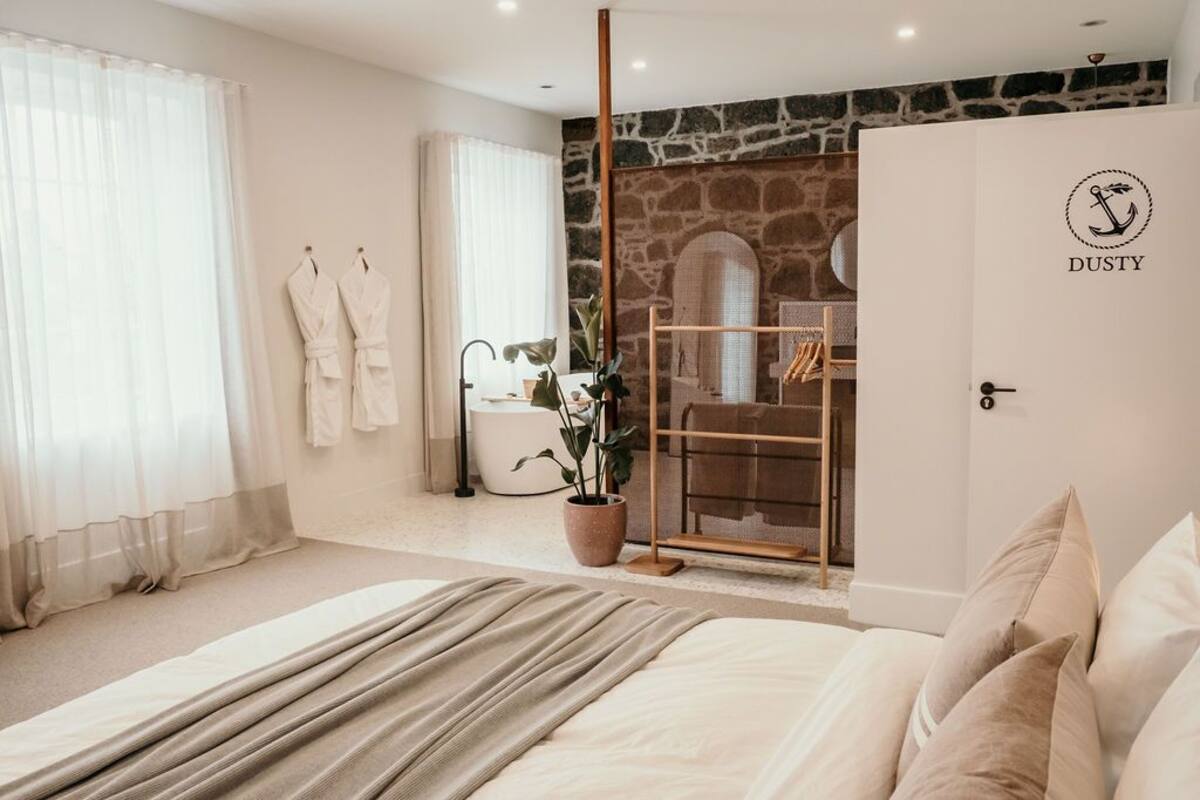 A bedroom with a large bed, a stone wall, and a door with a logo.