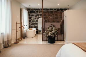 A modern bedroom with a large bed, a bathroom with a bathtub, and a potted plant. - The Oak & Anchor Hotel (Port Fairy)