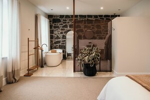 Un dormitorio moderno con una cama grande, un baño con bañera y una planta en maceta.