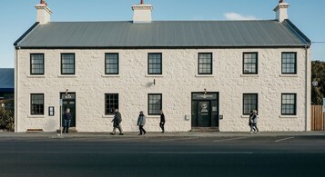 A white building with a bar and accommodation sign, multiple windows, and a flat roof.