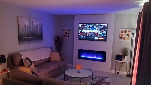 Una sala de estar con un sofá, una mesa de centro y un televisor de pantalla plana montado en la pared.