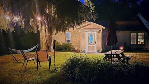 Una casa de madera con un porche, una hamaca, una mesa de picnic y una bandera.