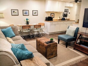 Un salon avec un canapé, une table basse, un fauteuil bleu et une valise ancienne.