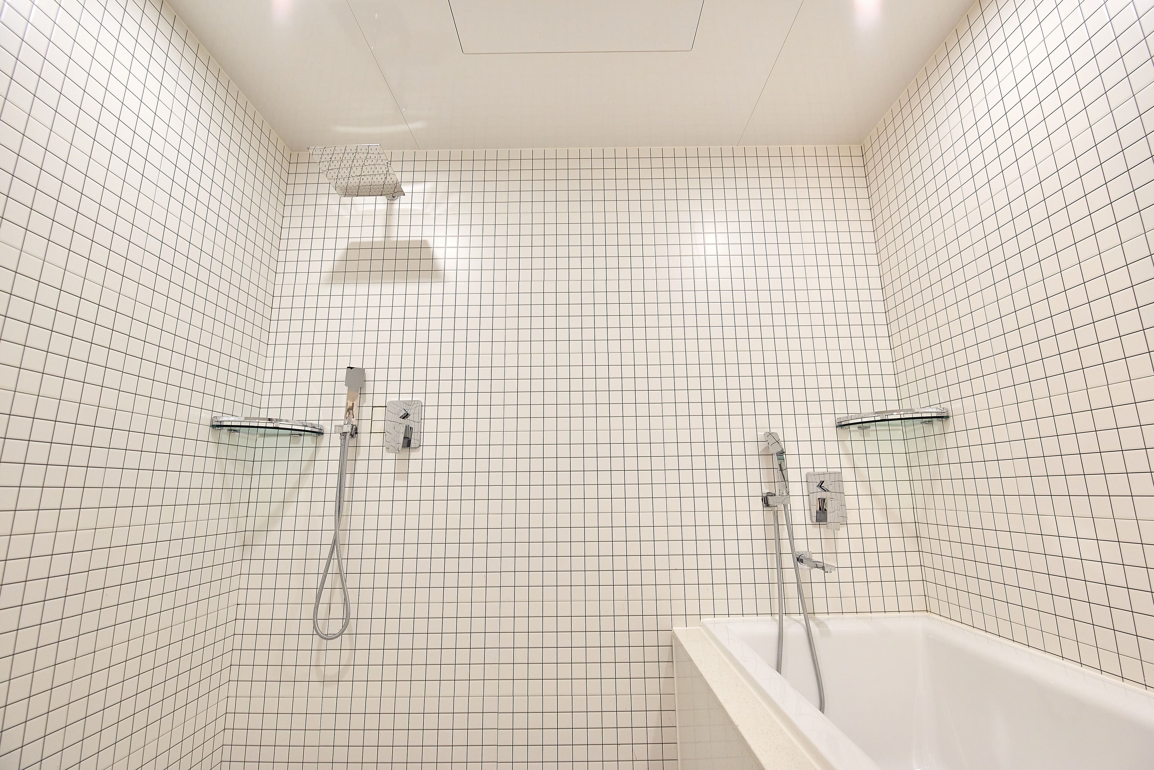 Un baño con paredes de azulejos blancos y una bañera blanca.