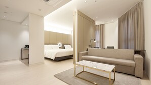 Una habitación de hotel moderna con una cama, un sofá, una mesita de centro y un escritorio.