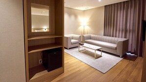 Una habitación de hotel moderna con un armario de madera, un sofá, una mesita de centro y una lámpara de pie.