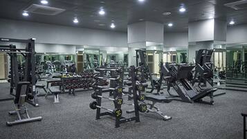 Une salle de sport équipée de divers appareils d’exercice, de miroirs et dotée d’un sol recouvert de moquette.