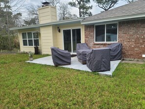 A house with a covered patio area, a brick exterior, and a lawn. - Historic Renovated Kemah Home just a short walk to the Kemah Boardwalk. (Kemah)