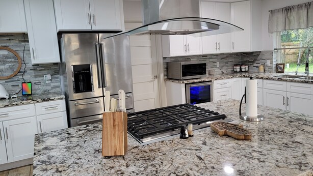 A modern kitchen with white cabinets, stainless steel appliances, and a granite countertop. - Historic Renovated Kemah Home just a short walk to the Kemah Boardwalk. (Kemah)