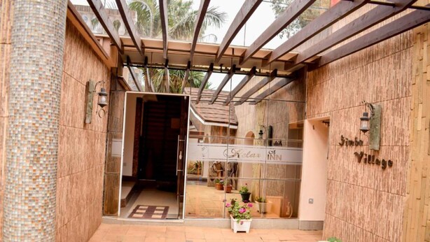 A hotel entrance with a wooden facade, a glass door, and a sign reading "Chicax Village". - Simba Village Relax Inn (Eldoret)