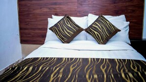 A bed with white bedding and two pillows with a zebra pattern. - Simba Village Relax Inn (Eldoret)