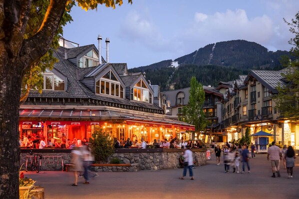 A restaurant with outdoor seating and a mountain view in the background.