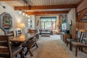 A cozy living room with a wooden dining table, sofa, and chairs.