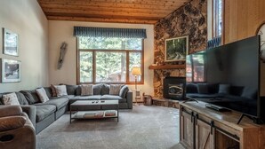 A cozy living room with a sectional sofa, a flat-screen TV, a fireplace, and a stone accent wall. - Spacious Winterset 26 2 Bedrm Plus Loft 3 Full Bathrm Townhome Sleeps 8 Steps to Free Town Shuttle (Mammoth Lakes)
