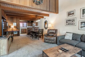 Una sala de estar acogedora con un sillón de cuero, un sofá, una mesa de centro y un comedor con una mesa y sillas de madera.