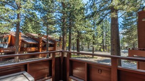 A wooden deck with a view of a cabin and tall pine trees. - Spacious Winterset 26 2 Bedrm Plus Loft 3 Full Bathrm Townhome Sleeps 8 Steps to Free Town Shuttle (Mammoth Lakes)