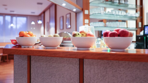 A hotel reception area with a wooden counter displaying bowls of fruit. - Hotel Blaubeurer Tor (Ulm)