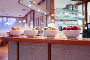 A hotel reception area with a wooden counter displaying bowls of fruit. - Hotel Blaubeurer Tor (Ulm)