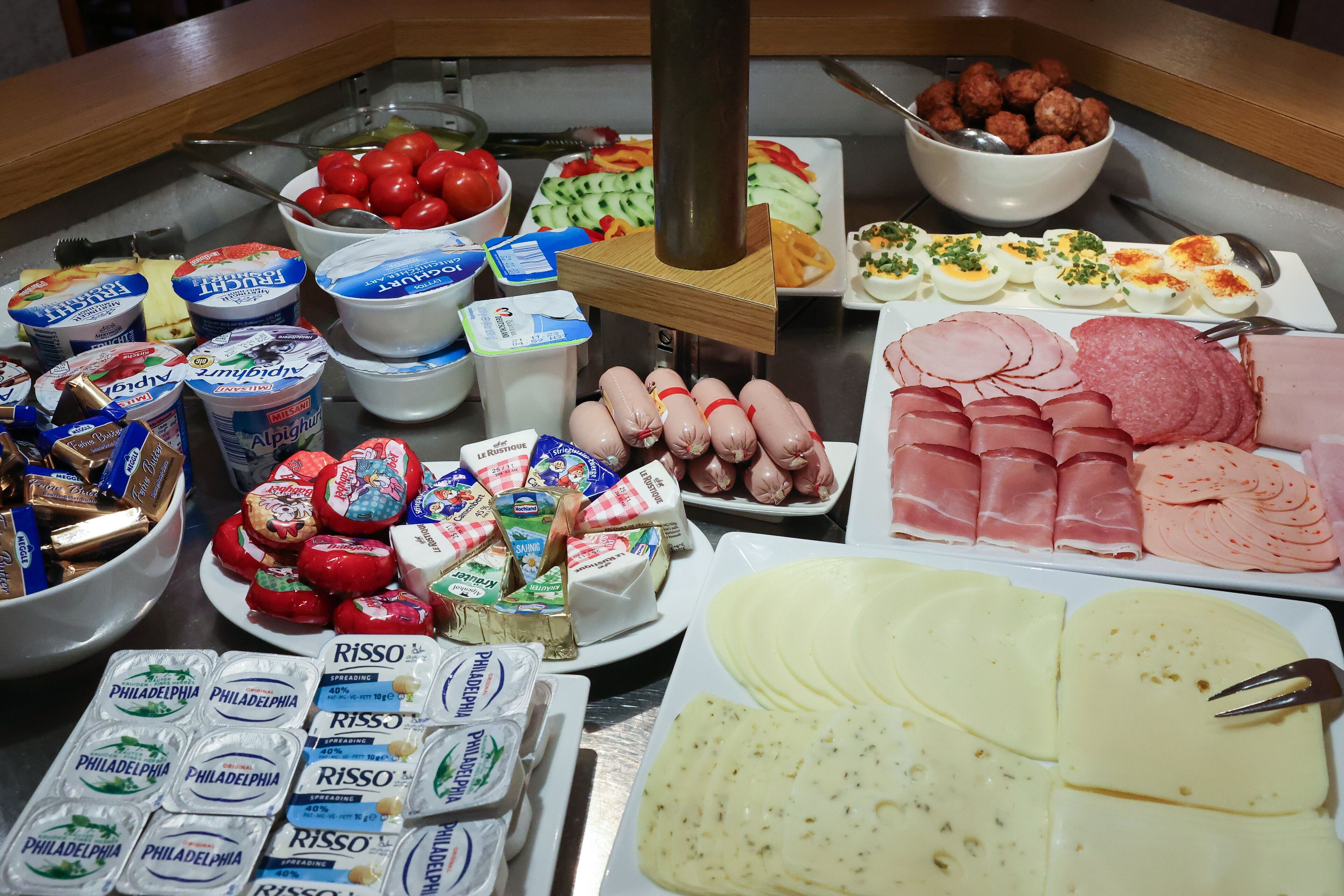 A buffet with various food items including cheeses, meats, and dairy products.