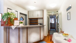 A reception area with a counter, a potted plant, framed certificates, and a small table with a bowl of fruit. - Hotel Blaubeurer Tor (Ulm)
