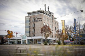 A multi-story hotel with a modern glass facade, a visible restaurant named 'Zarnekhut', and several banners advertising services. - Hotel Blaubeurer Tor (Ulm)