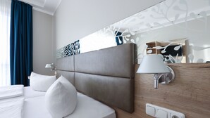 A modern hotel room with a large bed, a bedside lamp, and a wall-mounted power outlet. - Hotel Blaubeurer Tor (Ulm)