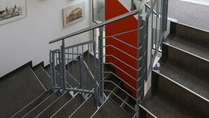 A modern staircase with metal railings and a red accent wall. - Hotel Blaubeurer Tor (Ulm)