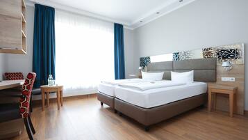 A modern hotel room with a large bed, a desk, and a chair.