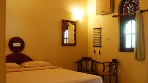 A bedroom with a bed, a chair, a mirror, and a window with curtains. - Dedduwa Boat House (Bentota)