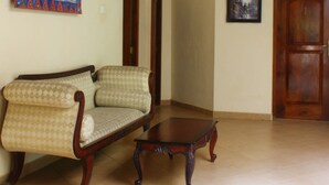 A living room with a sofa, a wooden coffee table, a wall-mounted light fixture, and a door. - Dedduwa Boat House (Bentota)