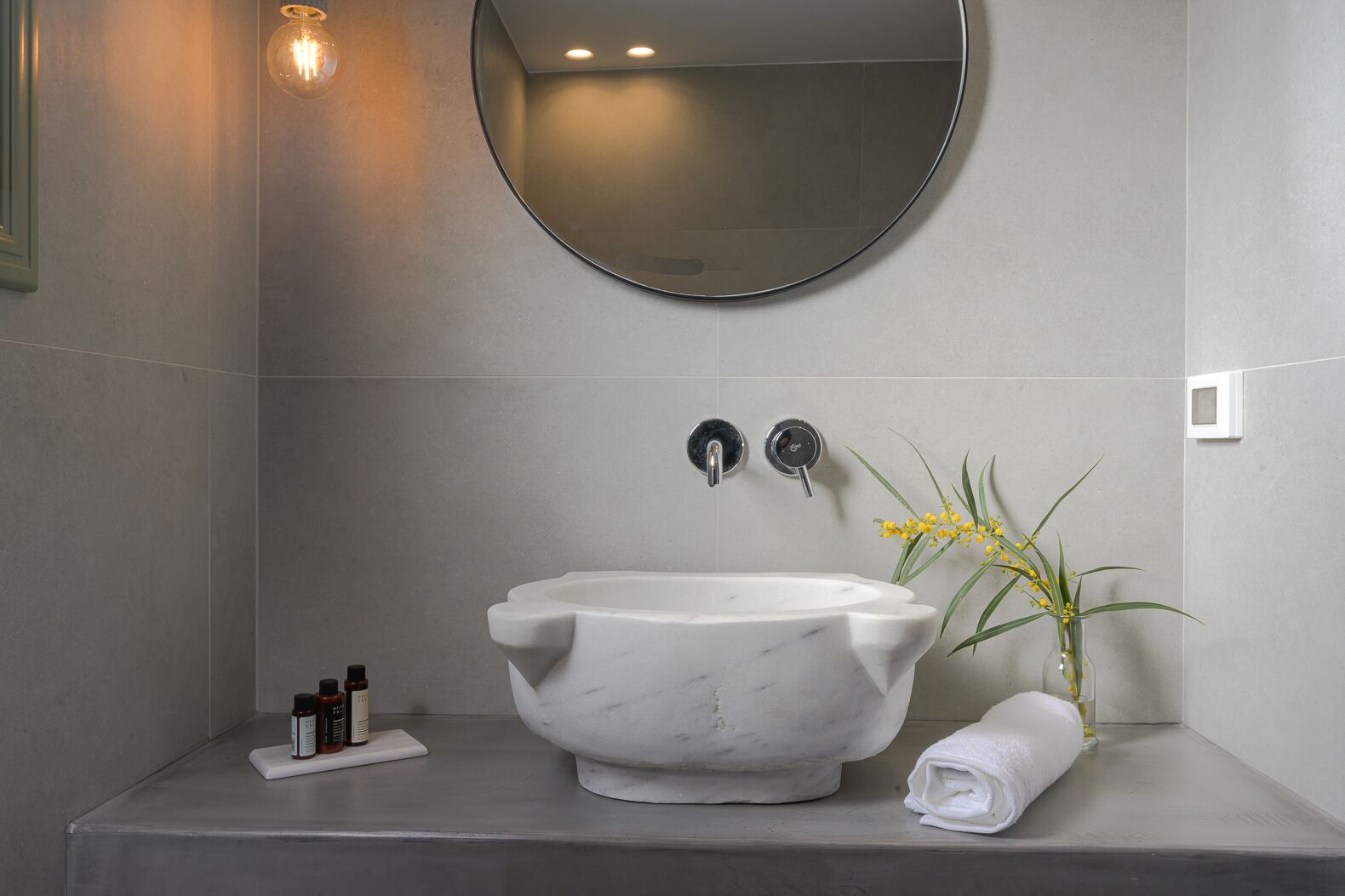 Un baño con un lavamanos de mármol independiente, un espejo y una planta pequeña.