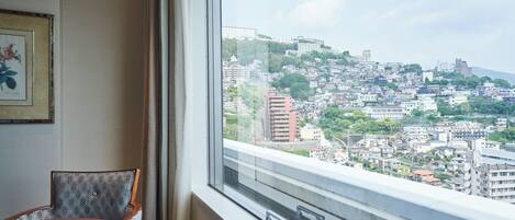 A room with a large window overlooking a densely packed urban area with various buildings and greenery.
