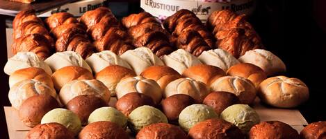 A variety of baked goods including bread, rolls, and pastries displayed on a wooden table.