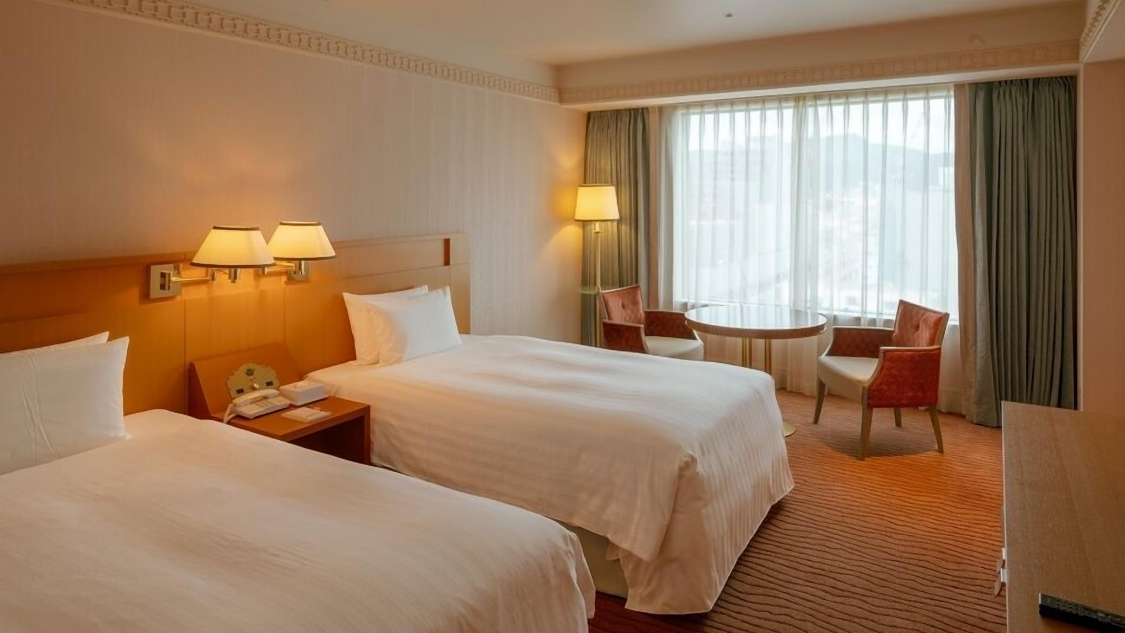 Ein Hotelzimmer mit zwei Betten, einem kleinen Tisch und einem Stuhl.