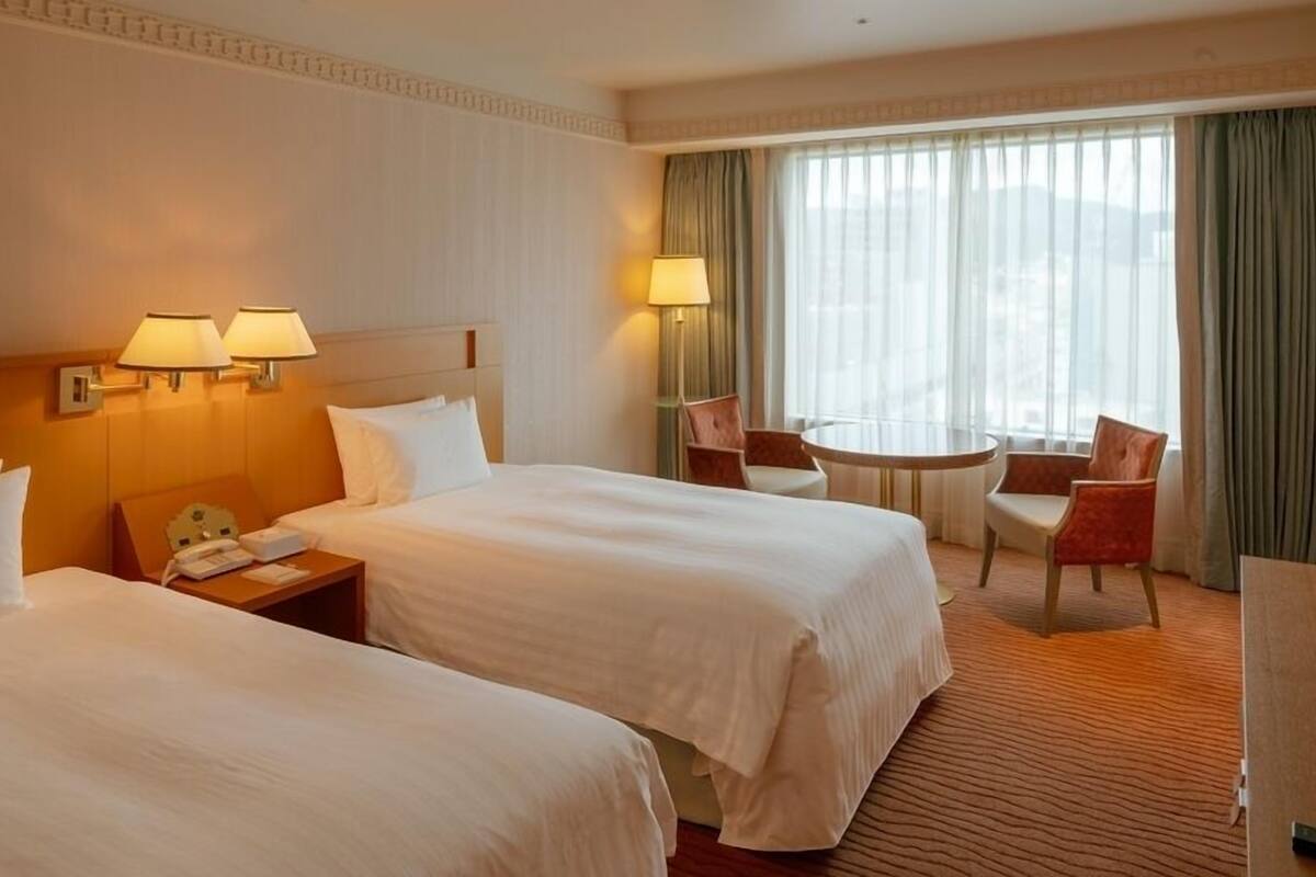 Ein Hotelzimmer mit zwei Betten, einem kleinen Tisch und einem Stuhl.