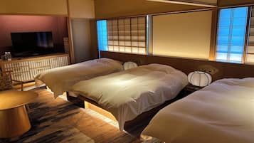 Une chambre d’hôtel avec deux lits, une télévision, une commode en bois et une vue sur la mer par les fenêtres.
