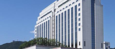 A modern multi-story building with a flat roof and a series of vertical windows.