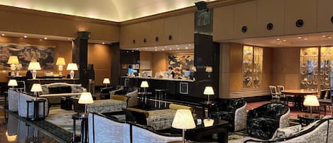A hotel lobby with a reception desk, seating area, and a reception wall with decorative items.