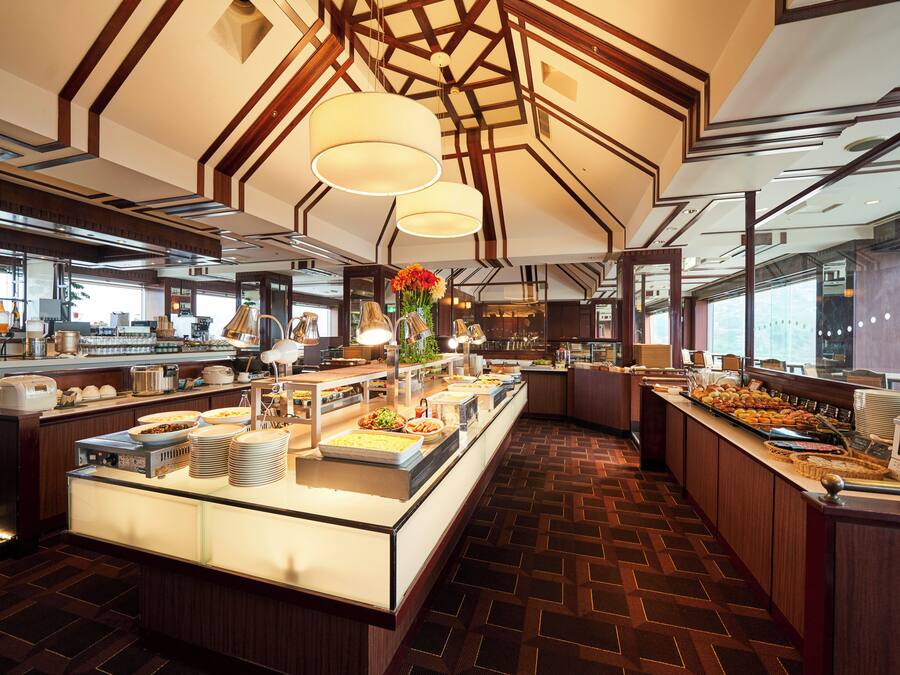 A buffet area with multiple food stations, a central island with a vase of flowers, and a modern ceiling design.