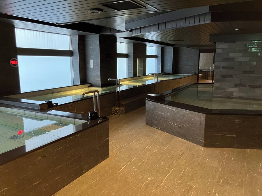 A modern bathroom with glass-enclosed sinks, a tiled floor, and a stone wall.