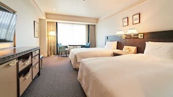 Ein Hotelzimmer mit zwei Betten, einem Schreibtisch, einem Stuhl, einem Fernseher und einem Fenster mit Vorhängen.
